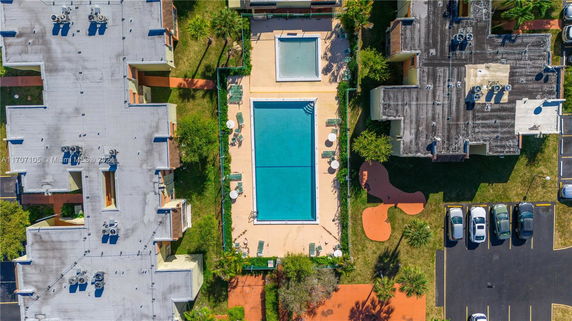 Aerial view of a large rectangular swimming pool surrounded by lounge chairs and tables.