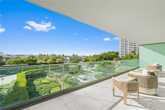 Spacious balcony with a modern design offering a wide view of a cityscape with trees and buildings.