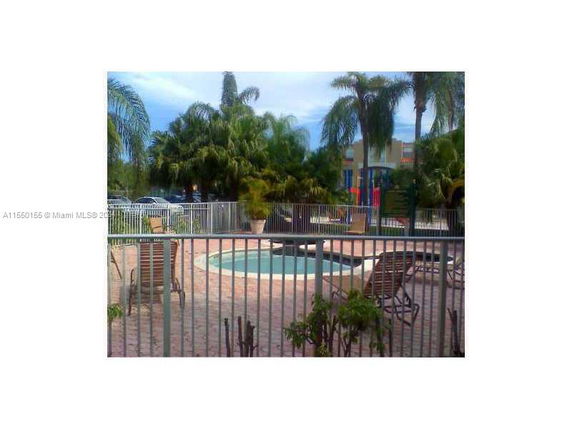 Outdoor area featuring a small swimming pool surrounded by a fence and lounge chairs.