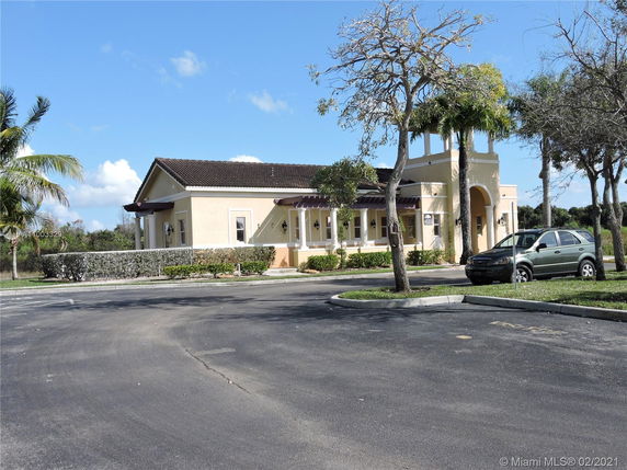 Front view of a single-story building with an arched entrance and brown roof.