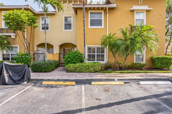 Front view of a two-story townhouse with a yellow facade and small front garden.