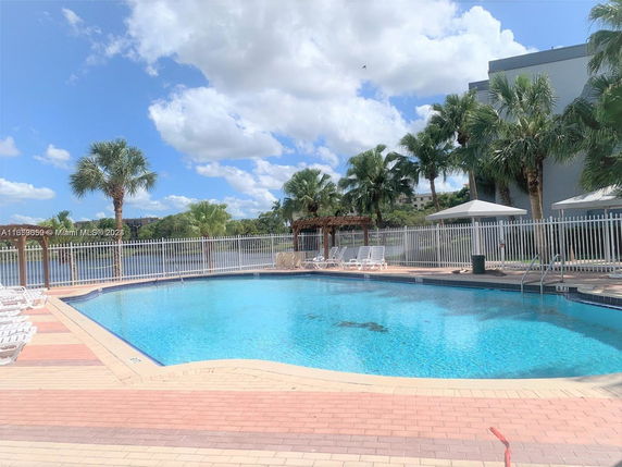 Outdoor swimming pool area with lounge chairs and umbrellas.