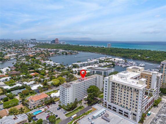 Aerial view of a coastal urban area with high-rise buildings, a marina, and the ocean in the background.