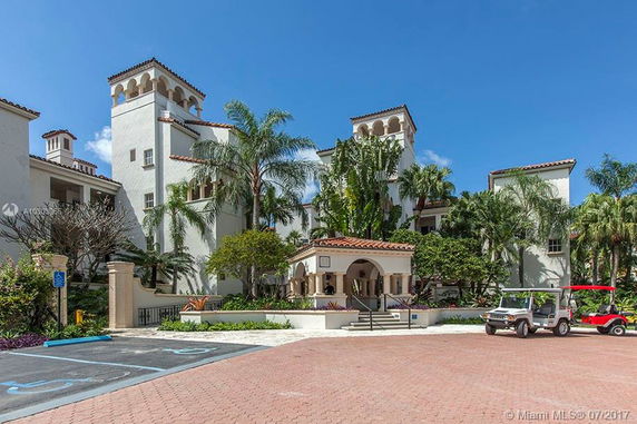 Front view of a large multi-story building with Mediterranean architectural features and palm trees.