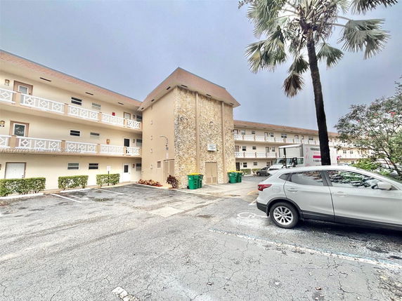 Front view of a multi-story residential building with parking area.