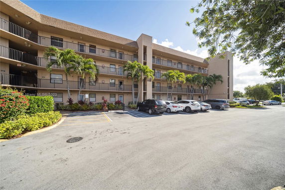 View of a multi-story building with parking area in front.