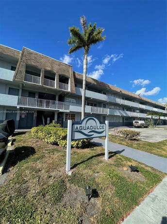 Front view of a multi-story building with balconies and a sign in front reading 'Aguadulce'.