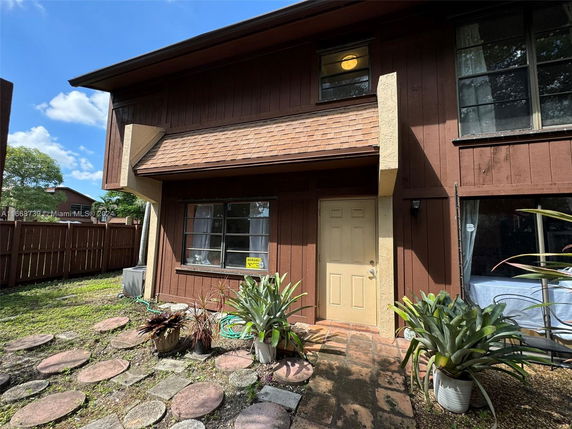 Front view of a two-story house with a wooden facade and a small front garden.