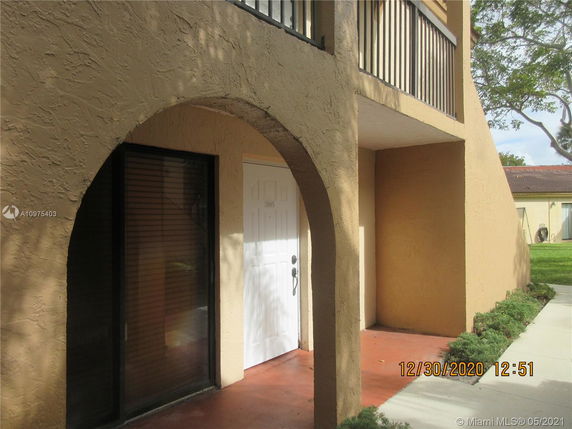 Front view of a two-story building with arched entrance and balcony.