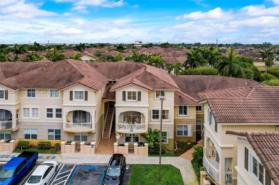 Front view of a multi-story residential building with balconies and tiled roofs.