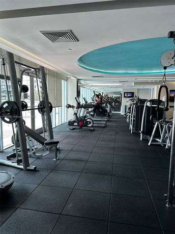 Indoor gym area with various exercise equipment and machines.