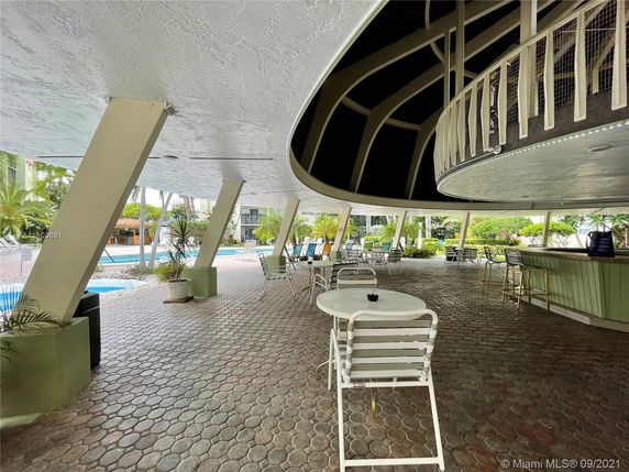 Poolside area with seating and shade structure.