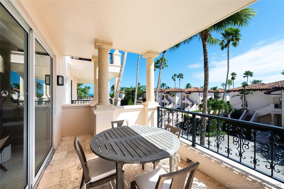 View from a balcony overlooking a complex with white buildings and red-tiled roofs, surrounded by palm trees.