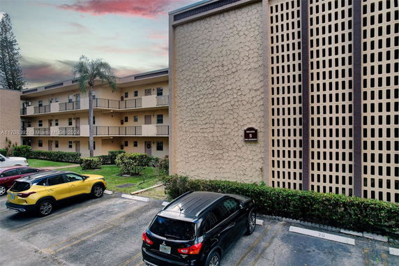 Front view of a multi-story residential building with balconies and parking area.