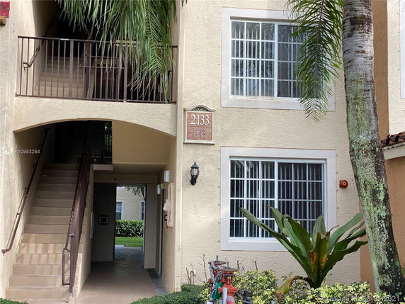 Front view of a multi-story building with exterior staircase and windows.