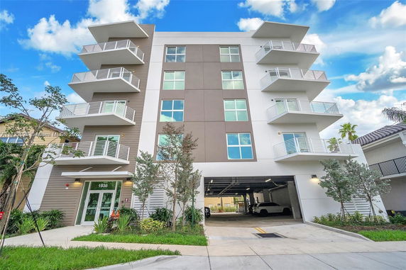 Front view of a modern multi-story apartment building with balconies.