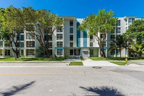 Front view of a multi-story residential building with trees in front.