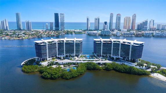 Aerial view of waterfront buildings with city skyline in the background.