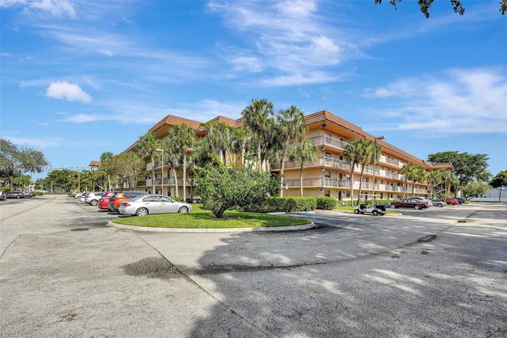 Front view of a multi-story residential building with balconies and palm trees.