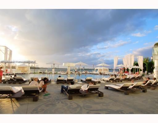 Outdoor swimming pool area with lounge chairs and umbrellas.