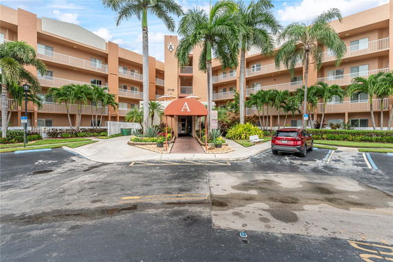 Front view of a multi-story residential building with balconies and palm trees.