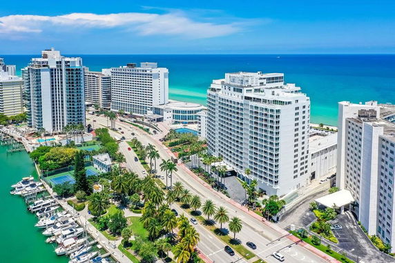 Aerial view of high-rise buildings along a coastal area with a visible shoreline and a marina.
