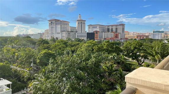 View of surrounding areas with several tall buildings and lush greenery.