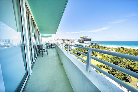Balcony with a view of a beach and nearby buildings.