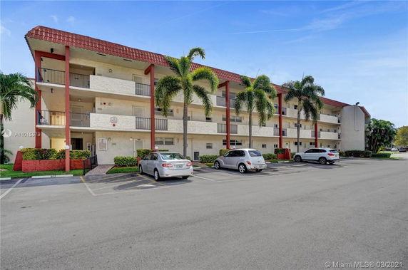 Front view of a three-story residential building with balconies and red accents.