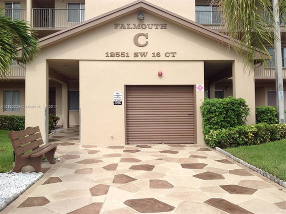 Front view of a multi-story residential building with a tiled pathway and garage door.