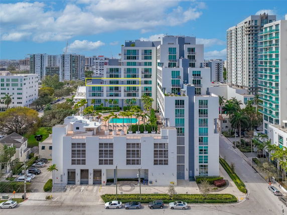 Front view of a multi-story apartment complex with balconies and a rooftop pool area.