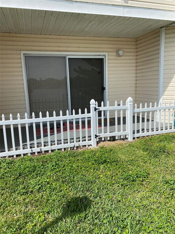 Exterior view of a house with sliding glass door and white fence.