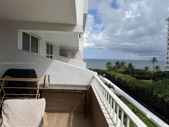 Panoramic view from a balcony overlooking the ocean and palm trees.