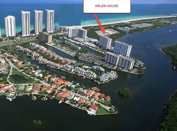 Aerial view of high-rise residential buildings near a body of water, with surrounding residential areas and coastline.