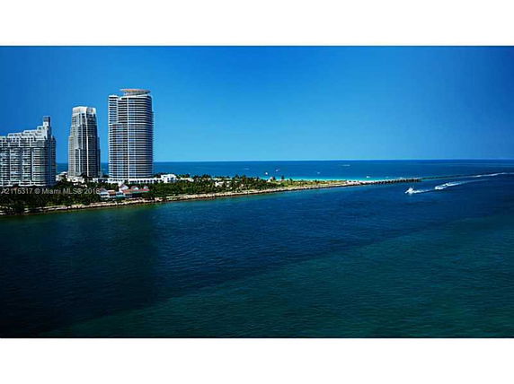 View of tall, modern high-rise buildings near the coast with ocean and shoreline in the background.