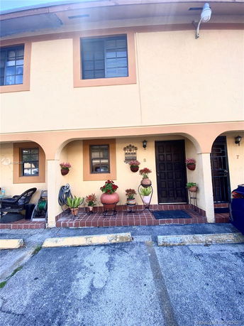 Front view of a two-story townhouse with decorative plants.