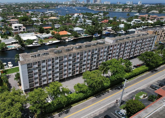 Aerial view of a multi-story building with a flat rooftop equipped with multiple air conditioning units.