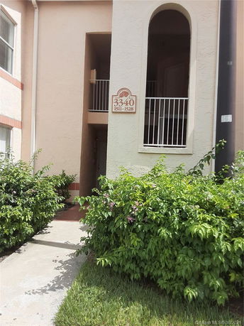 Entrance view of a residential building with a walkway and plants.