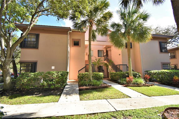 Front view of a two-story residential building with beige walls and dark window frames.