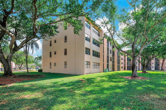View of apartment buildings surrounded by green lawns and trees.