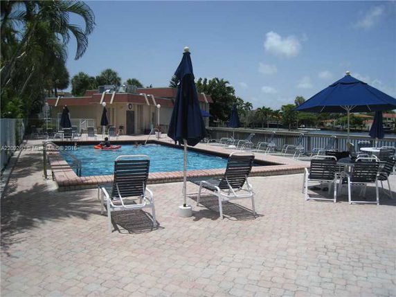 Outdoor swimming pool area with lounge chairs and umbrellas.