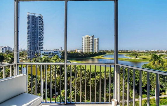 Panoramic view from a balcony overlooking a golf course and tall buildings in the distance.