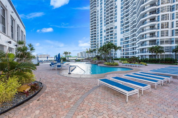 Outdoor view of a high-rise building with a pool area and lounge chairs.