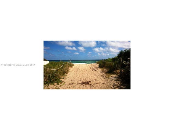 Pathway leading to a sandy beach with ocean view.