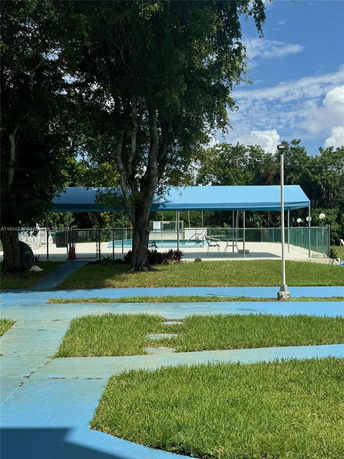 Outdoor swimming pool with a blue canopy and surrounding greenery.