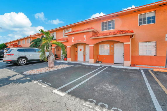 Front view of a two-story building with orange walls and visible parking spaces.
