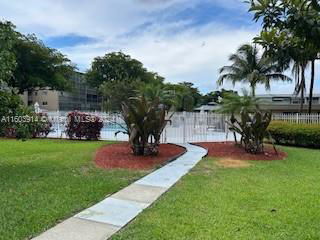Outdoor view of a swimming pool area surrounded by greenery and pathways.