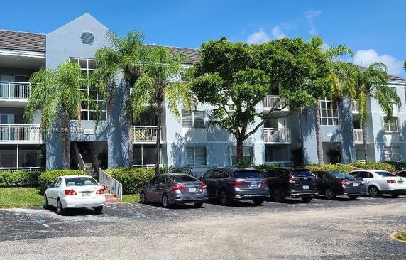 Front view of a multi-story residential building with a parking area in front.