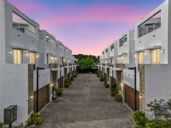 View of a row of modern multi-story townhouses with white facades and balconies.