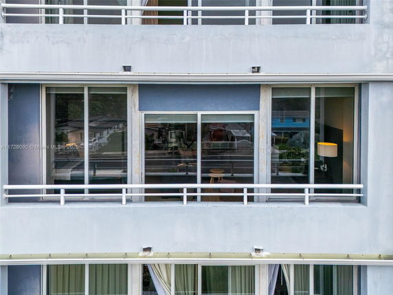Front view of an apartment building with large windows and balcony railings.